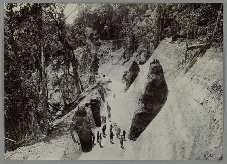 Construction of the road along the southern slope at Woih ni Tanggo Besi. There are fossils in the hillside. Tipped-in photo in an album with 107 photos about the construction of the Gajoweg in North Sumatra between Bireuen and Takinguen between 1903-1914.