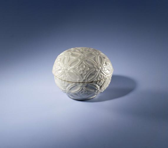 Porcelain spherical box with lid, covered with a gray glaze. The box is covered with a continuous embossed floral pattern. Two cracks in the lid. Two old labels in the box with 'from winch'. Ming porcelain.